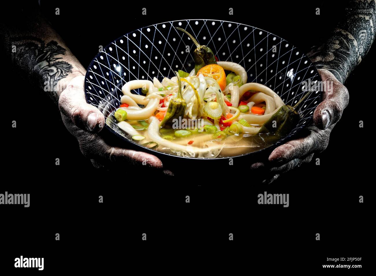 Assiette à mains tatouées avec bol à udon, soupe de nouilles japonaises Banque D'Images