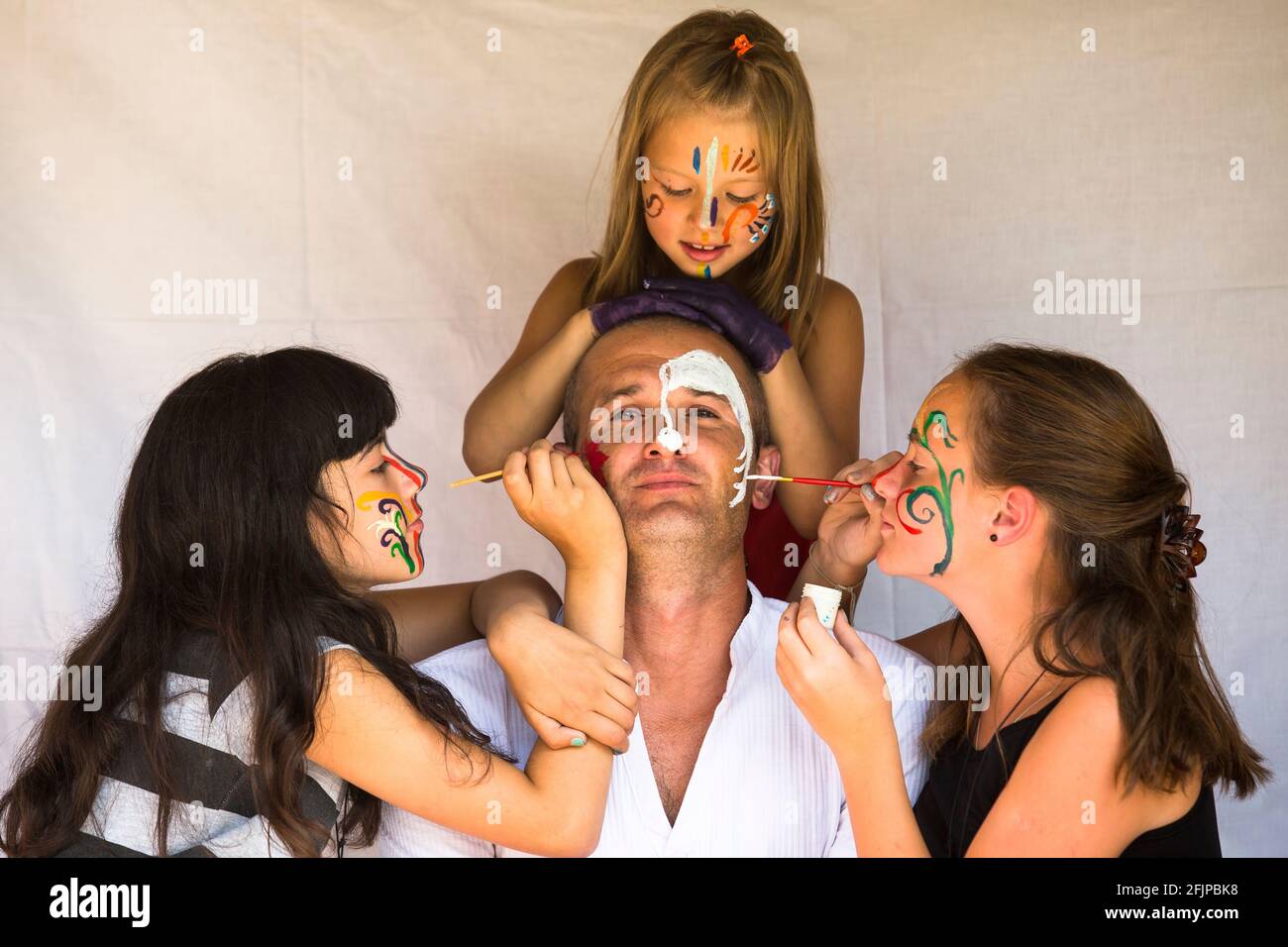 Famille heureuse - enfants filles peint le visage de son père. Banque D'Images