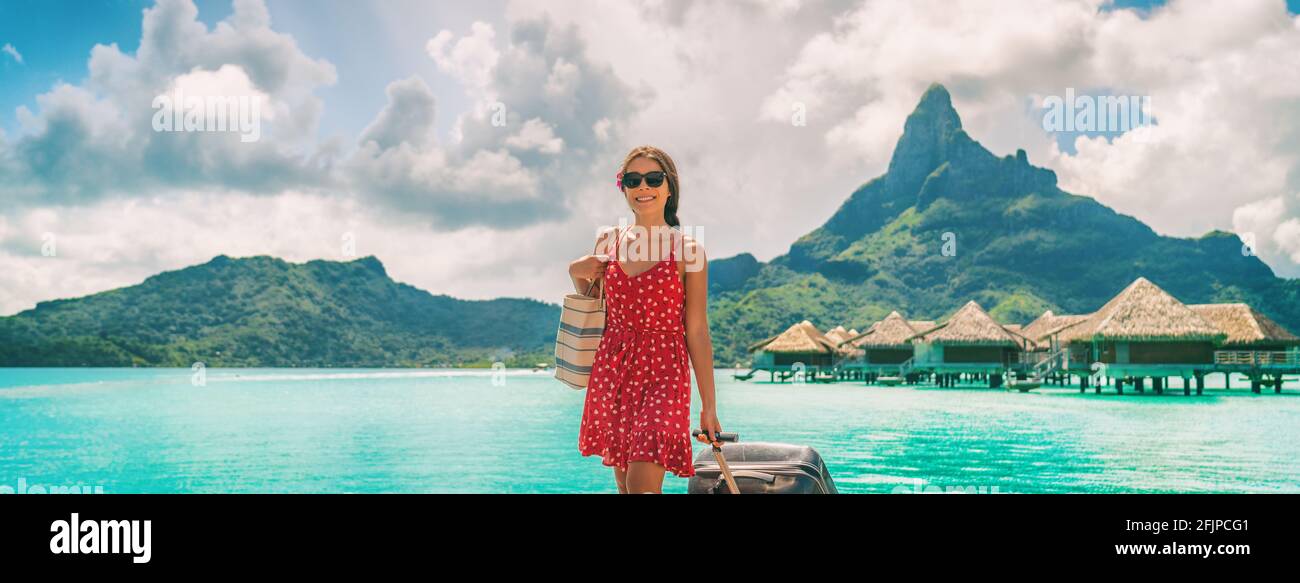 Une femme voyageant à pied avec ses bagages en Polynésie française sur Paradise Motu sur Bora Bora avec le Mont Otemanu. Femme arrivant en vacances de rêve Banque D'Images
