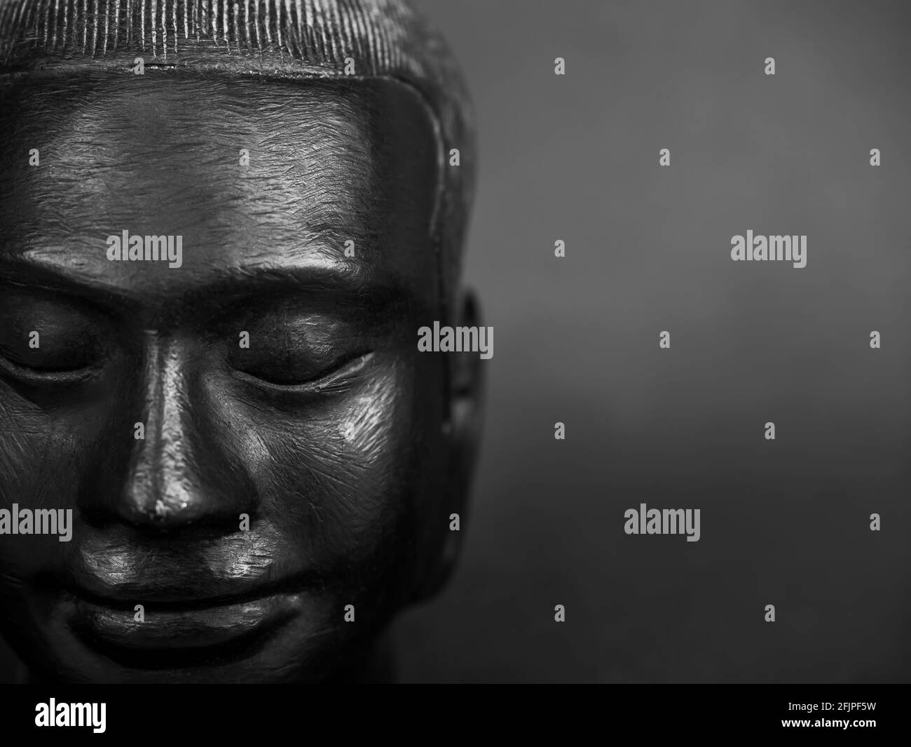 Tête de Bouddha, couleur noire sculptée de pierre sur fond sombre avec espace de copie. Vue rapprochée de bouddha antique en pierre, vue de face. Banque D'Images