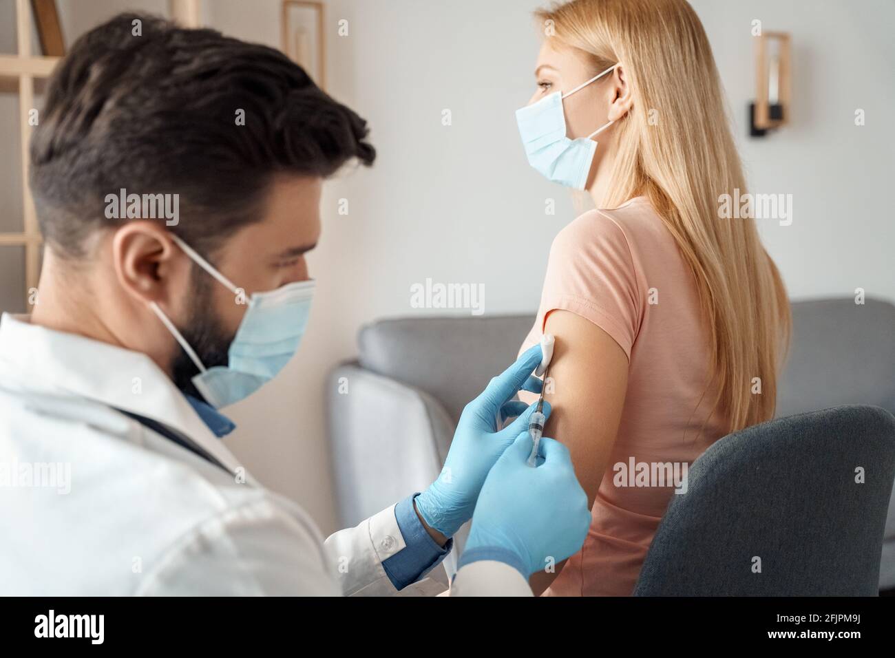 Une femme de race blanche portant un masque facial se fait vacciner contre le covid-19 à la clinique bureau Banque D'Images