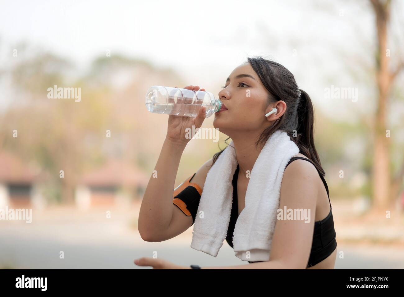 Belle athlète de forme physique femme buvant de l'eau après l'entraînement au lever du soleil matin l'été dans le parc Banque D'Images