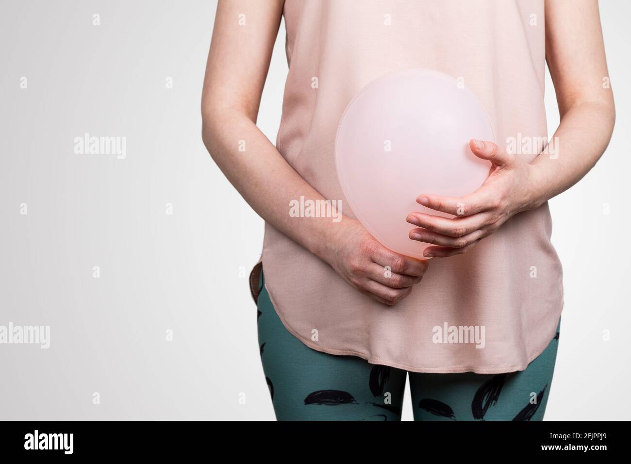 Femme enceinte ou ballonnement du ventre. Ballon rose dans les mains de la  femme. Arrière-plan abstrait Photo Stock - Alamy