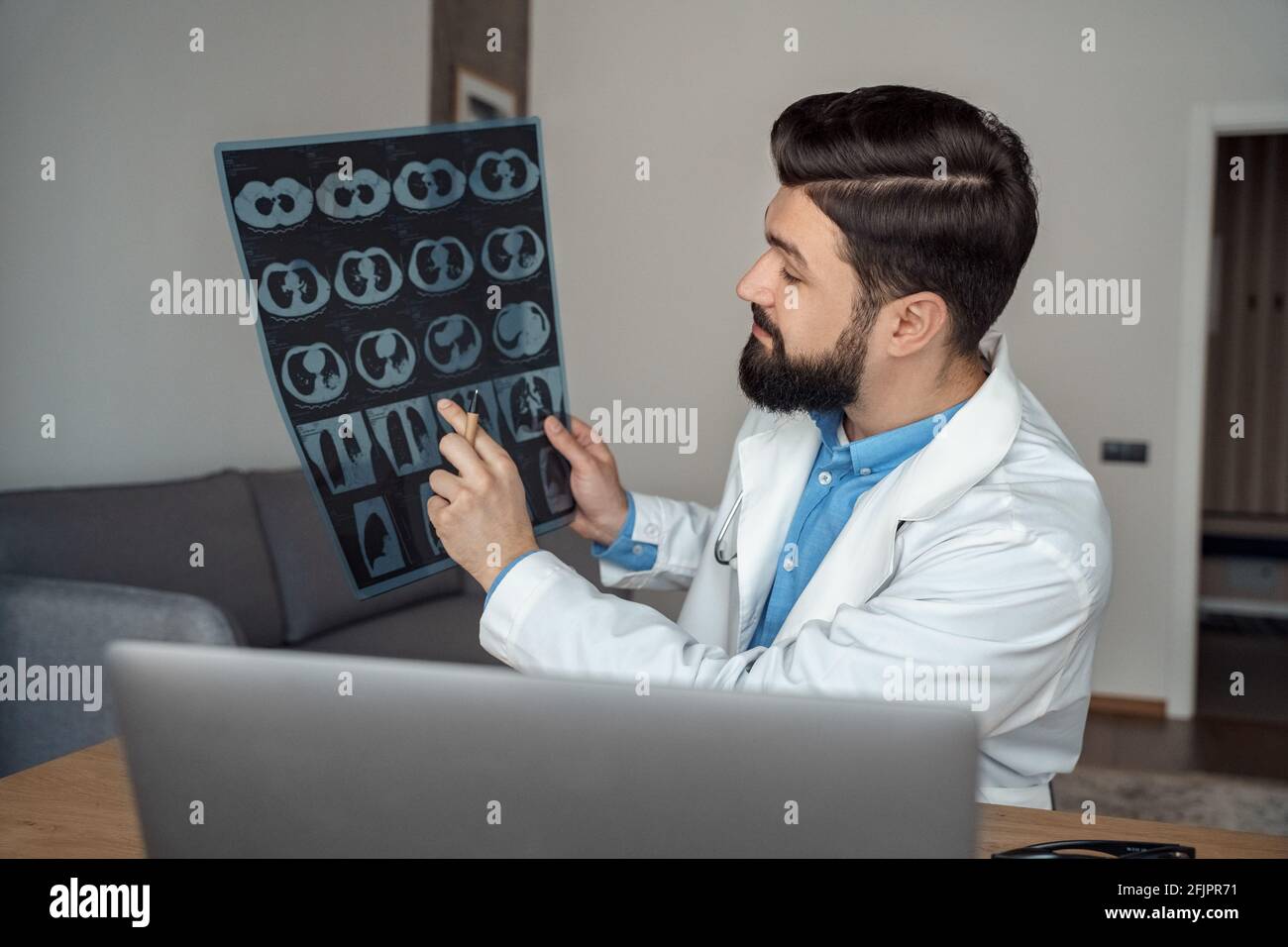 Jeune médecin de sexe masculin discutant de la radiographie des poumons pendant la vidéo-conférence sur ordinateur portable Banque D'Images