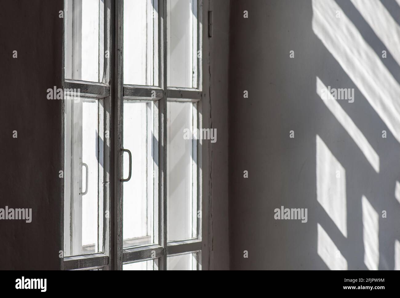 Intérieur de la pièce avec fenêtre, cadre, lumière du soleil et ombres sur le mur Banque D'Images