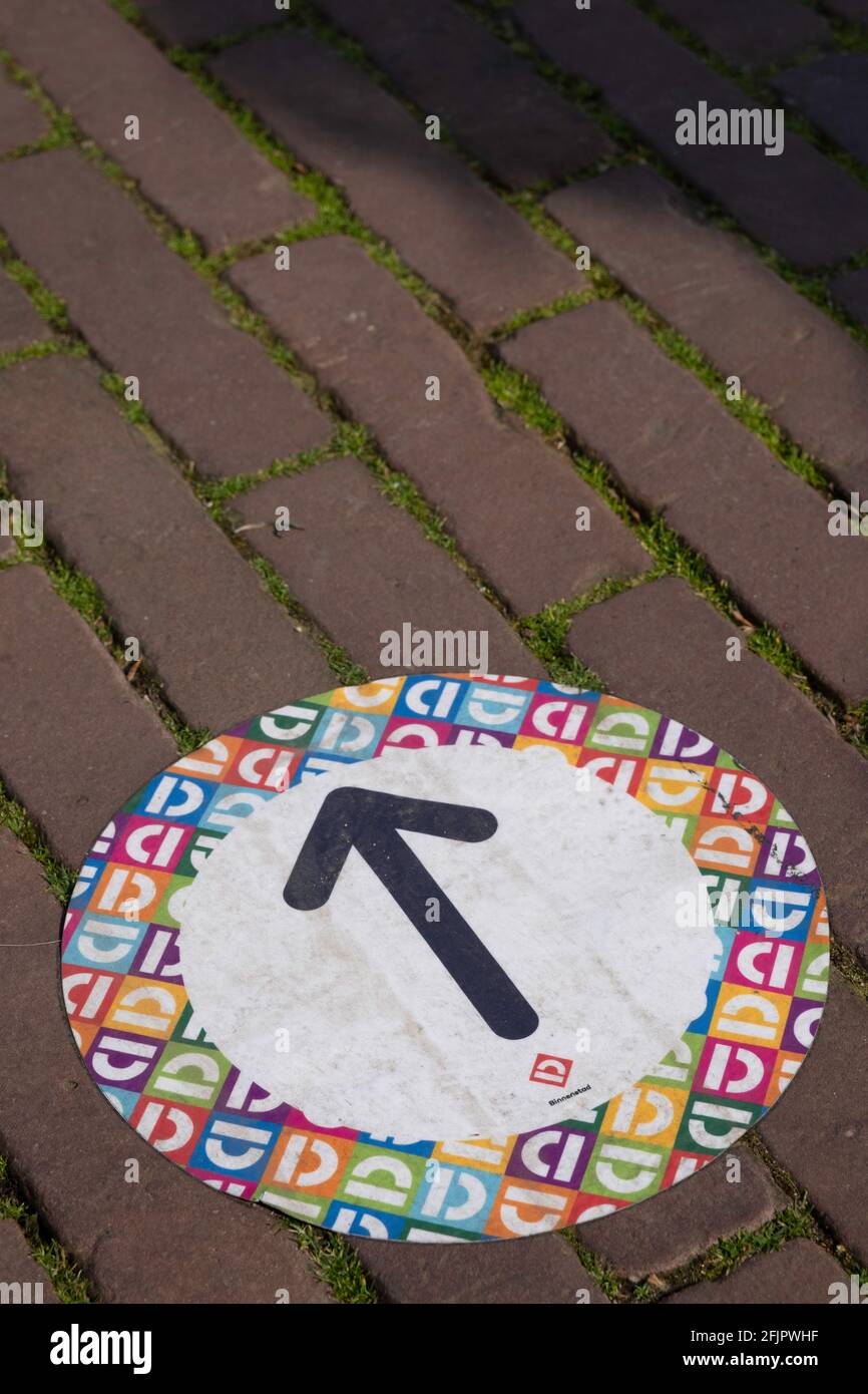 Flèche noire sur un autocollant rond de couleur sur les finisseurs pour indiquer la direction de la marche dans une rue commerçante Pour éviter toute contamination par Corona Banque D'Images
