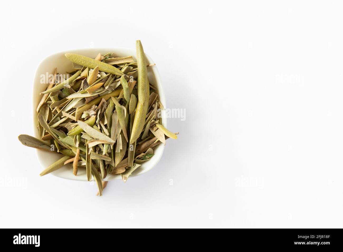 Feuilles d'olive séchées sur le sol et dans une assiette blanche. Espace de copie, espace pour le texte. Banque D'Images