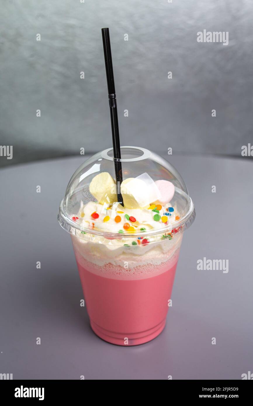 cocktail rose laiteux dans un verre en plastique. Banque D'Images