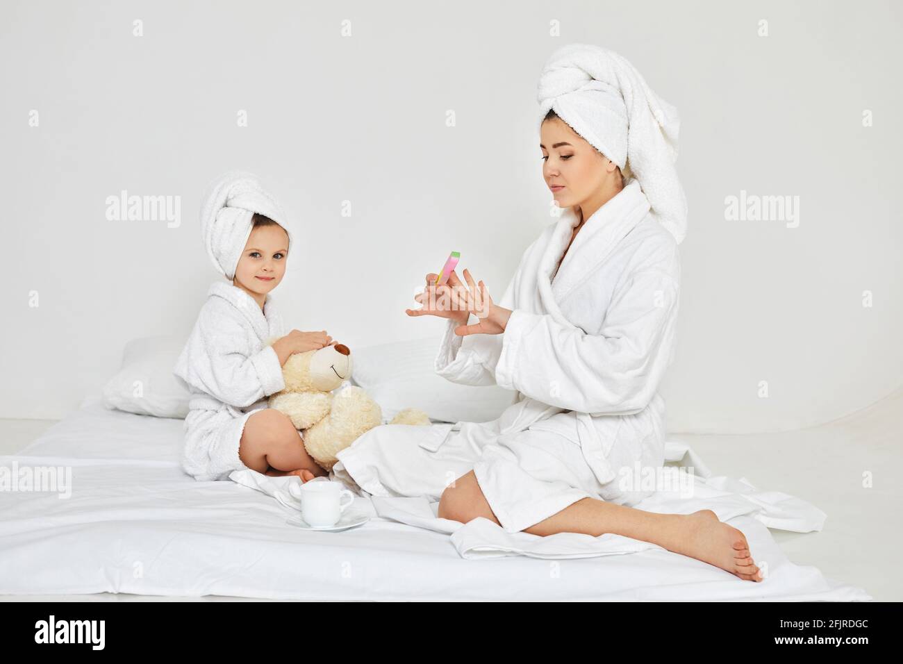 la mère fait de la manucure et la fille joue avec l'ours en peluche Banque D'Images