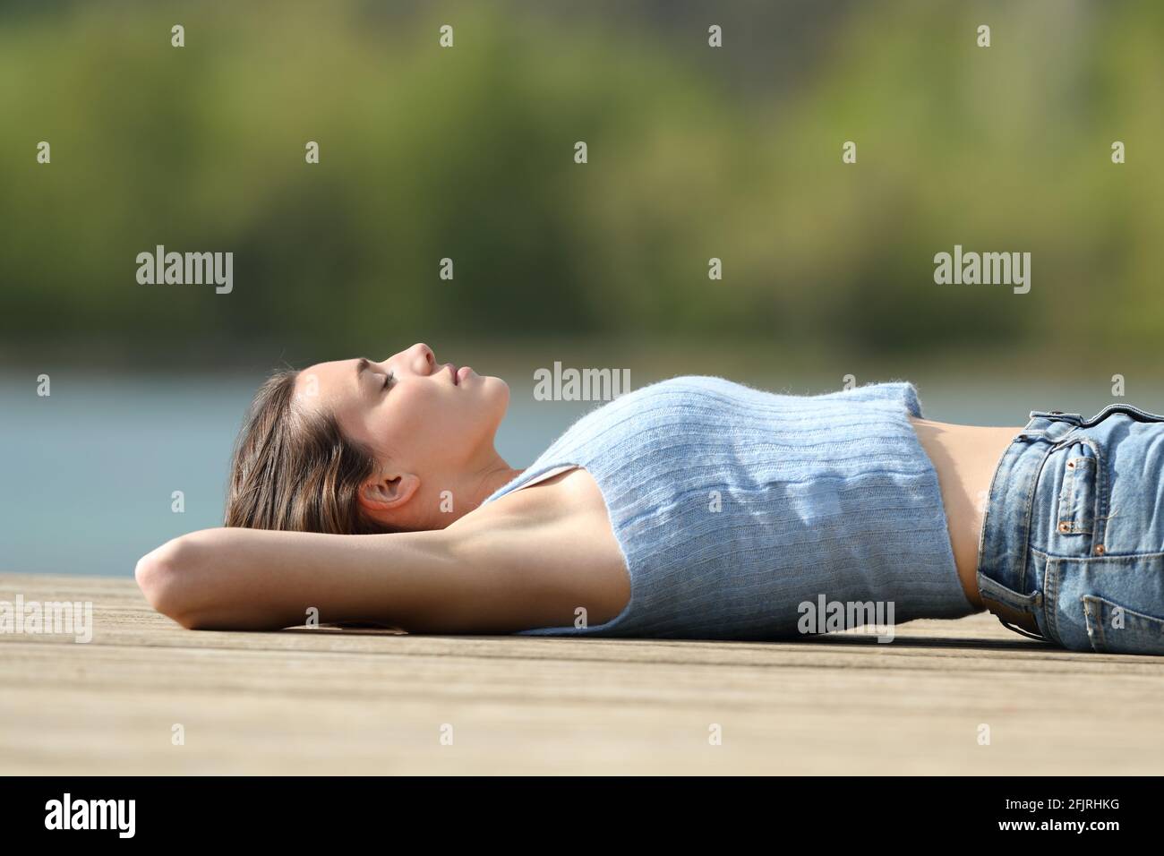 Vue latérale d'une femme détendue allongé une jetée sur le lac en vacances d'été Banque D'Images