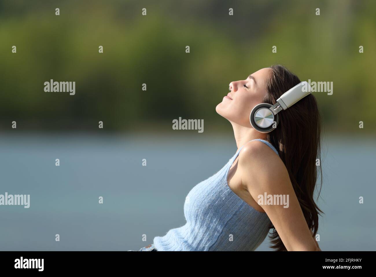 Portrait d'une femme décontractée portant un casque d'écoute sur le côté à la musique dans un lac Banque D'Images