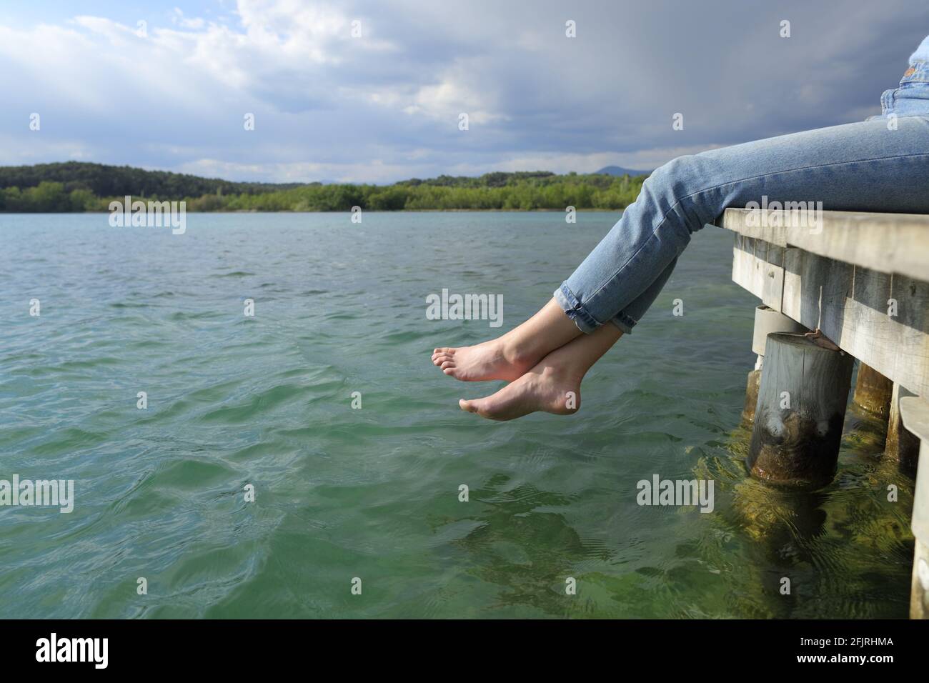 Vue latérale de près des jambes et des pieds d'une femme repos assis dans un lac jetée Banque D'Images