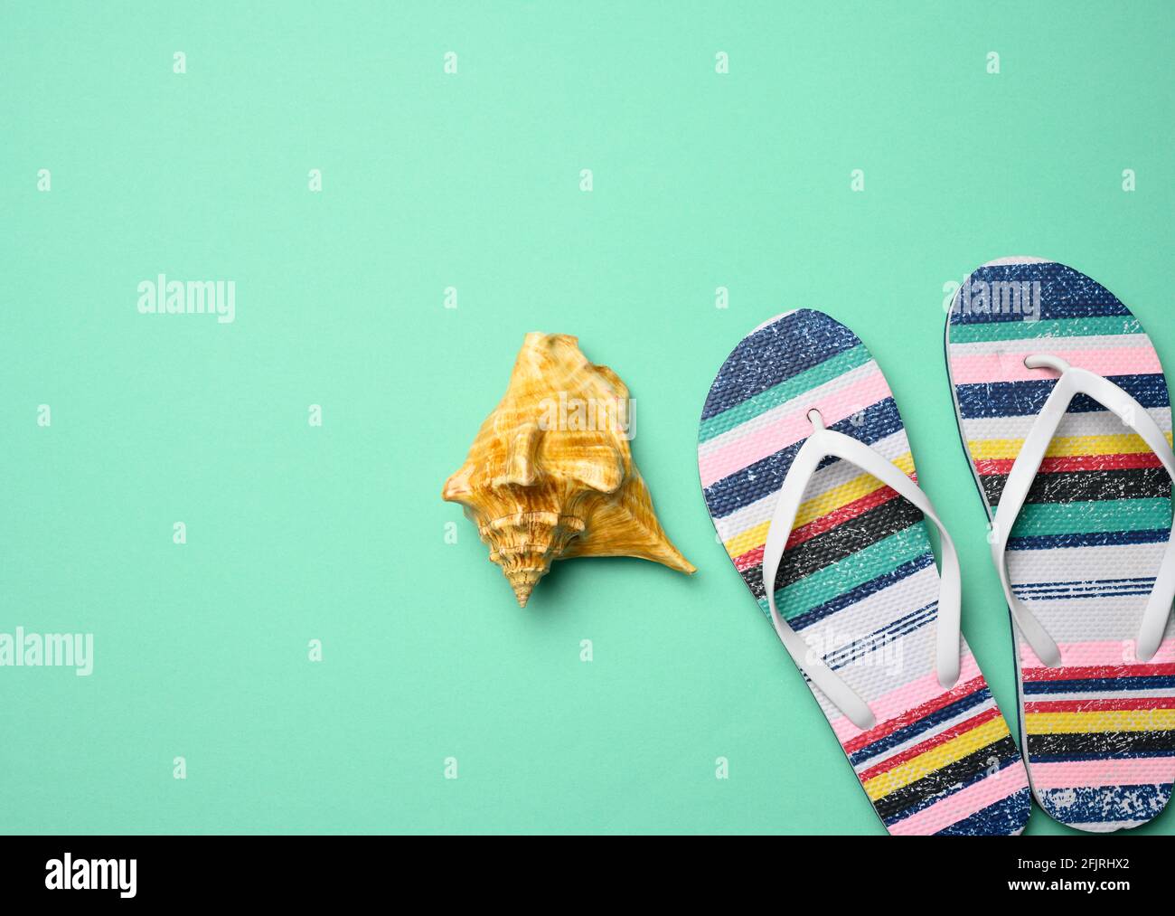 pantoufles multicolores pour femmes et seashell sur fond vert, vue du dessus Banque D'Images