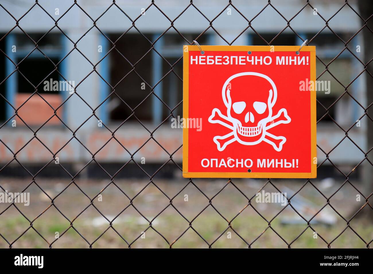 Conflit armé à l'est de l'Ukraine, guerre ukrainienne. Signe rouge avec crâne et crossones, inscription en ukrainien et russe - mines de danger. Banque D'Images
