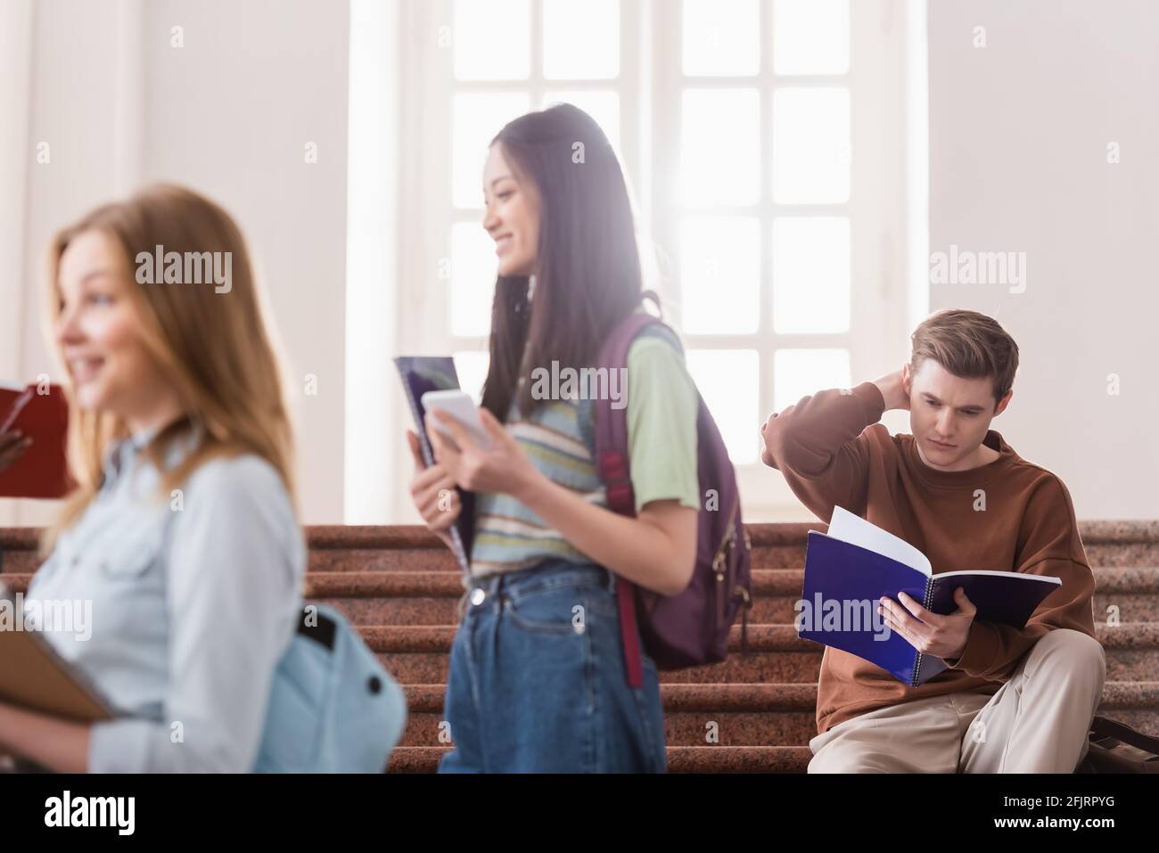 Étudiant regardant un ordinateur portable près de personnes multiethniques sur un premier plan flou Banque D'Images