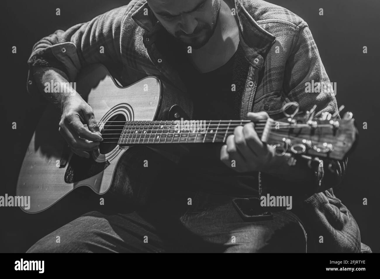 Le musicien joue de la guitare dans une pièce sombre. Banque D'Images