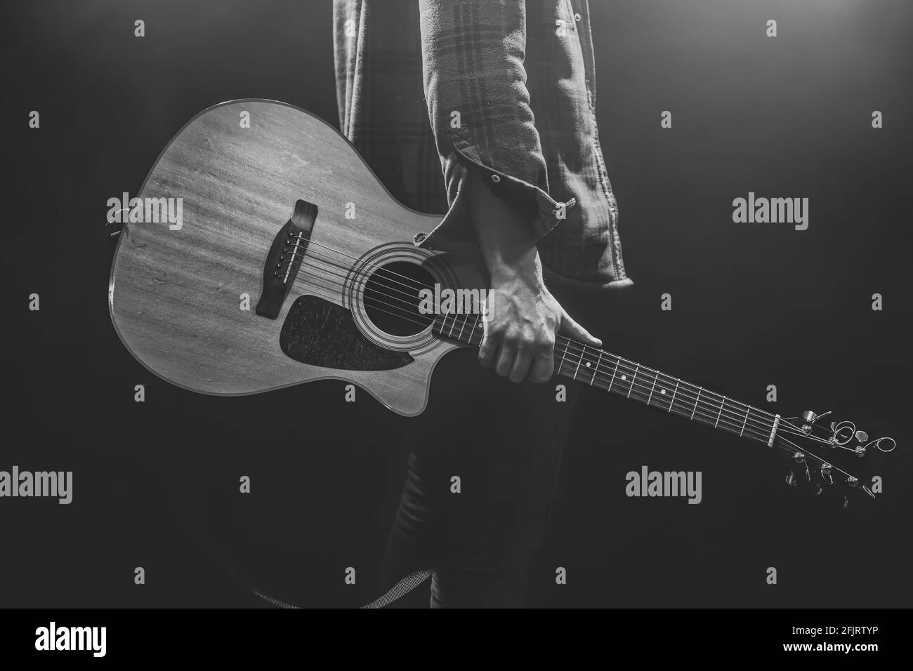 Un homme tenant une guitare acoustique dans ses mains de près. Banque D'Images