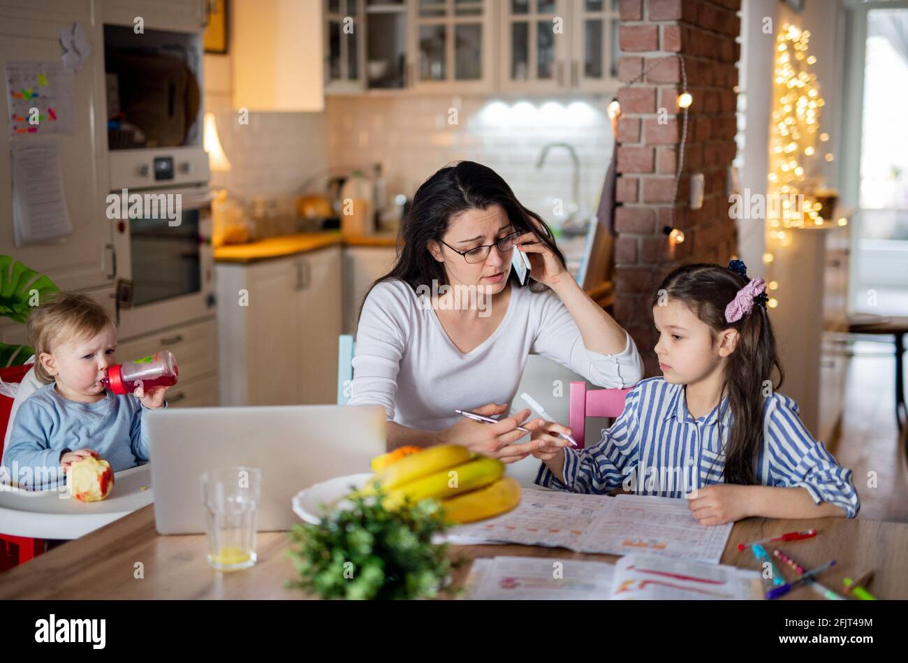 Mère avec petite fille dans la cuisine, école à domicile, bureau et apprentissage à distance concept. Banque D'Images