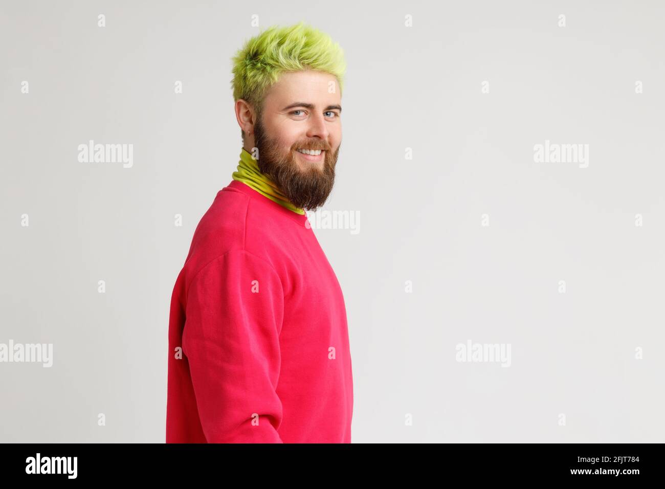 Profil de l'homme caucasien à barbe gaie a l'expression heureux sourires largement, a blanc dents parfaites, porte le chandail rouge, regarde la caméra. Copier l'espace Banque D'Images