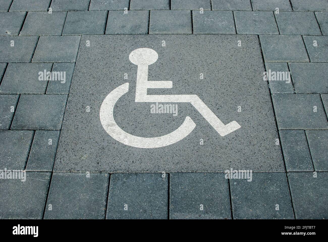 Panneau de stationnement pour handicapés peint sur la surface en pierre de la route du stationnement Banque D'Images