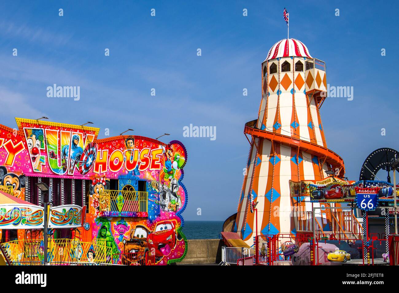 Vue sur le parc des expositions de Hunstanton avec le Helter Skelter et la Crazy Fun House dans des couleurs éclatantes. Banque D'Images