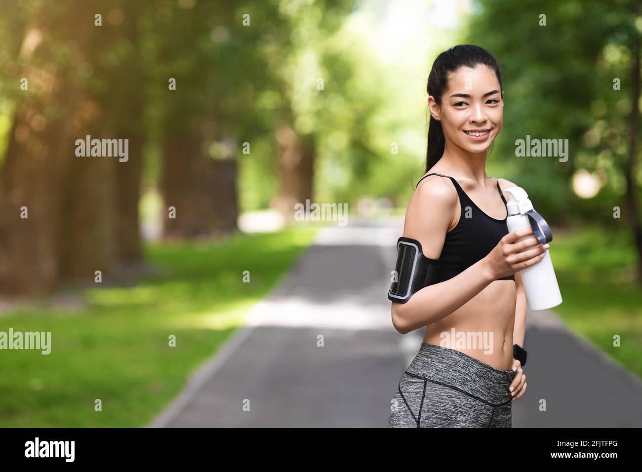 Athlétique jeune fille asiatique en train de faire une pause dans l'entraînement en plein air, eau potable Banque D'Images