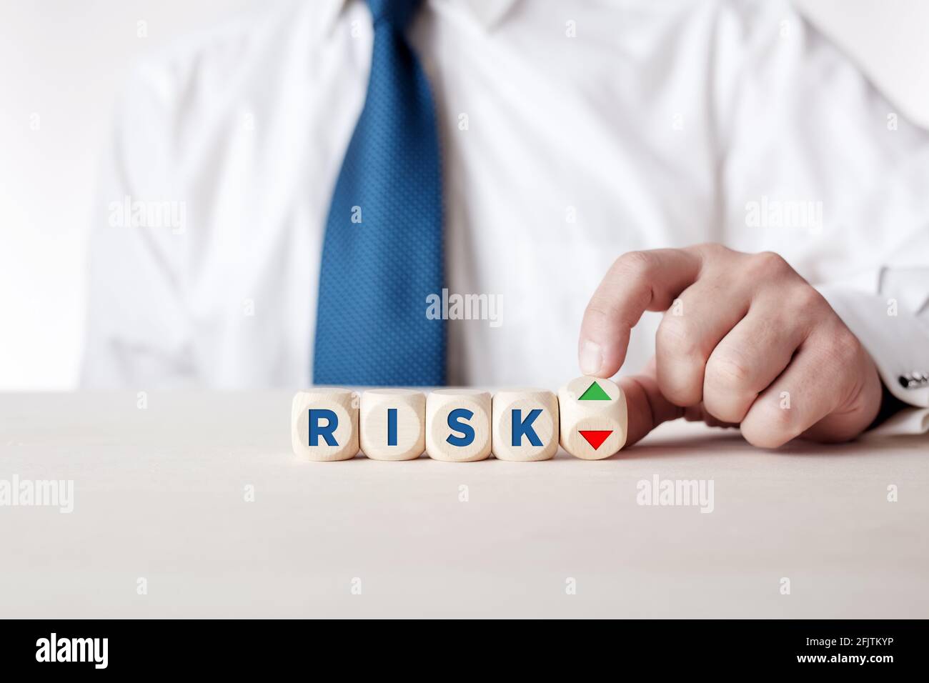 La main d'homme d'affaires tourne un cube en bois avec les flèches symbolisant le niveau de risque est élevé ou faible. Banque D'Images
