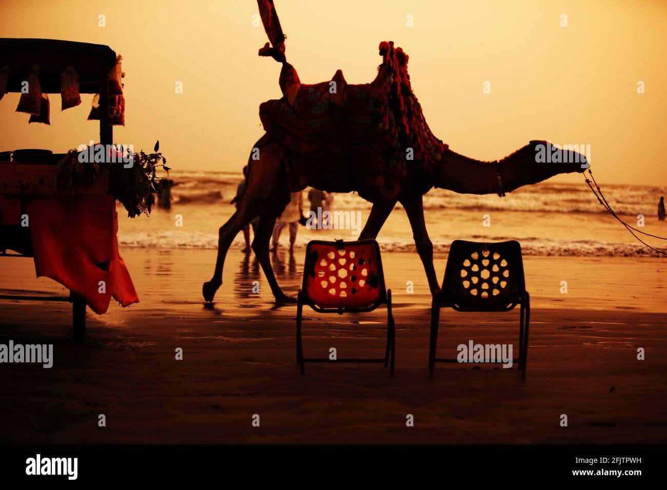 Karachi, Pakistan : propriétaire de chameaux marchant avec un chameau pour attirer la foule sur la plage de Clifton Beach à Karachi, Pakistan. Clifton Beach a.k.a Seaview est m Banque D'Images