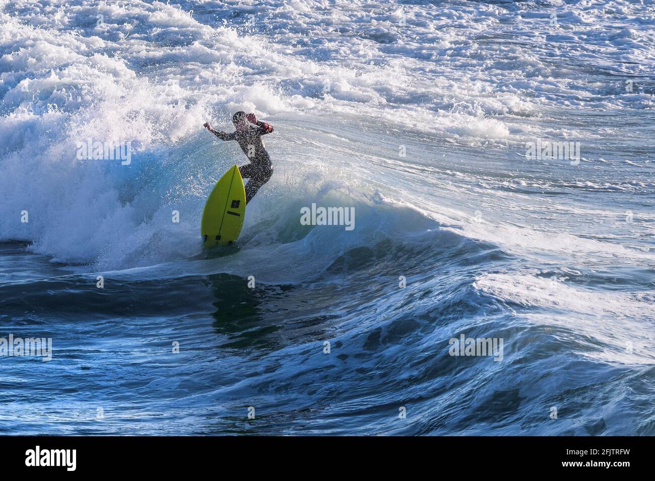 Un surfeur qui s'aprise d'une vague à Fistral, à Newquay, en Cornouailles. Banque D'Images