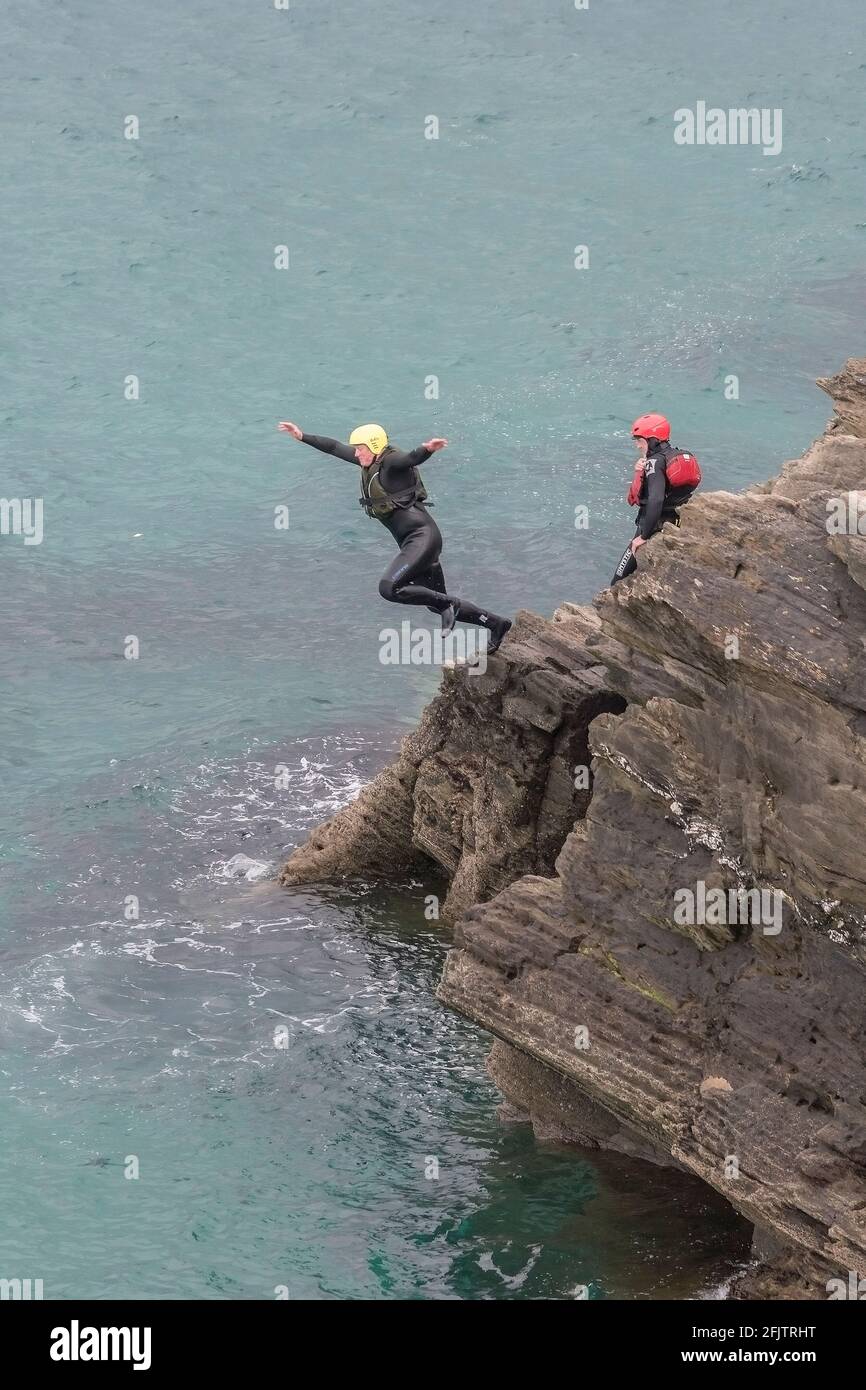Un vacanciers qui bonde des rochers pendant une séance de copilotage autour de la zone intertidale de Towan Head à Newquay, en Cornouailles. Banque D'Images