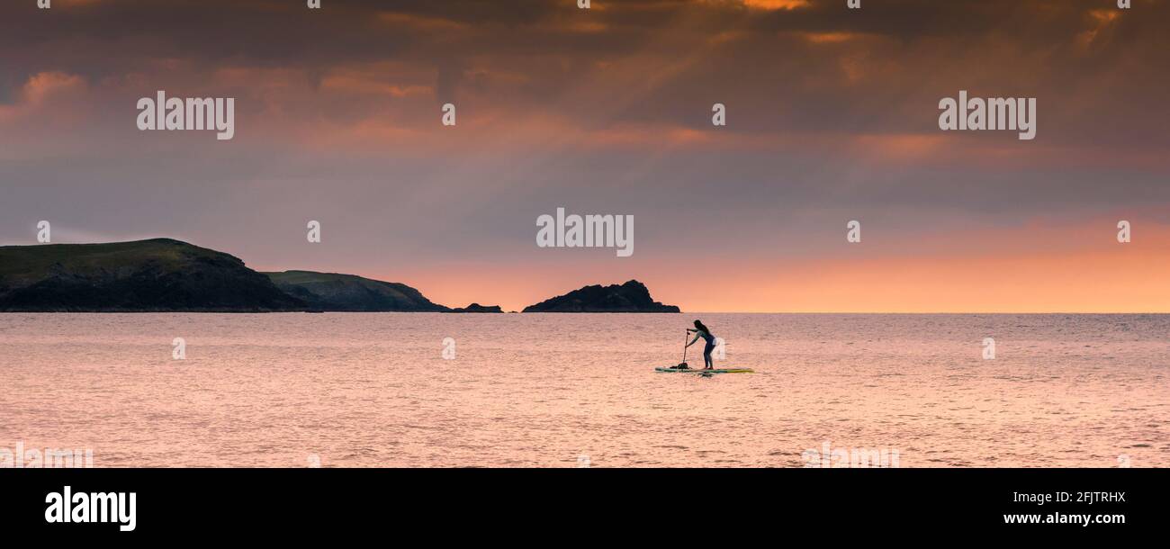 Image panoramique d'une femelle debout Paddleboarder pagayant pendant un coucher de soleil doré dans la baie de Fistral à Newquay en Cornouailles. Banque D'Images