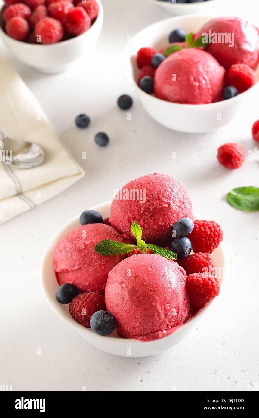 Cuillère à crème glacée à la framboise avec framboises fraîches et bleuets dans un bol sur fond de pierre. Dessert d'été froid Banque D'Images