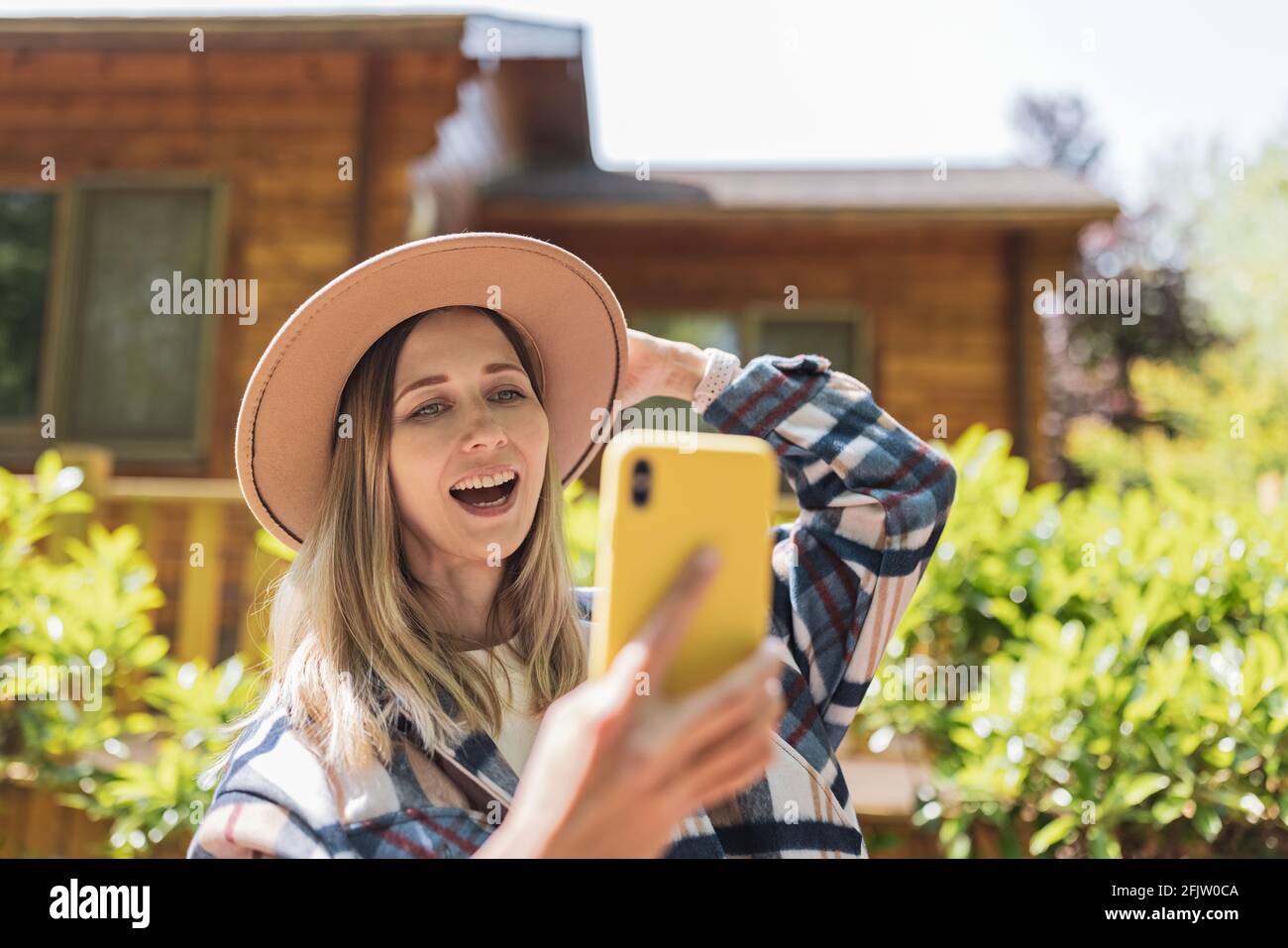 Jeune femme caucasienne élégante de 30-35 ans portant des vêtements décontractés chemise et chapeau de cow-boy. Influenceur utilisant les médias sociaux par téléphone mobile. Personne Banque D'Images