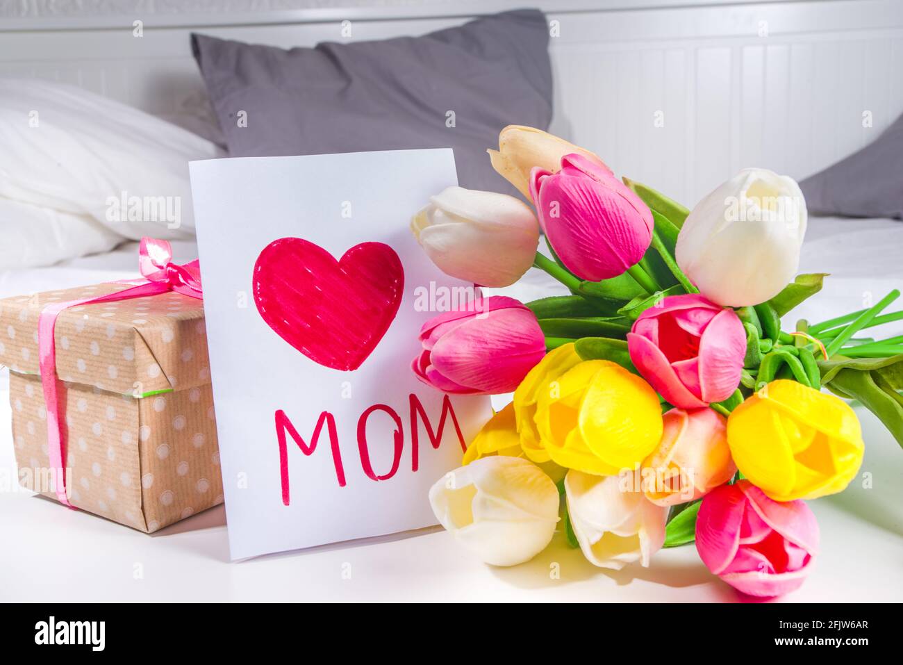 Fête des mères, fête des filles concept de style de vie. Enfant jeune fille blonde jeune fille avec un bouquet de fleurs de tulipe, carte de vœux faite à la main Banque D'Images