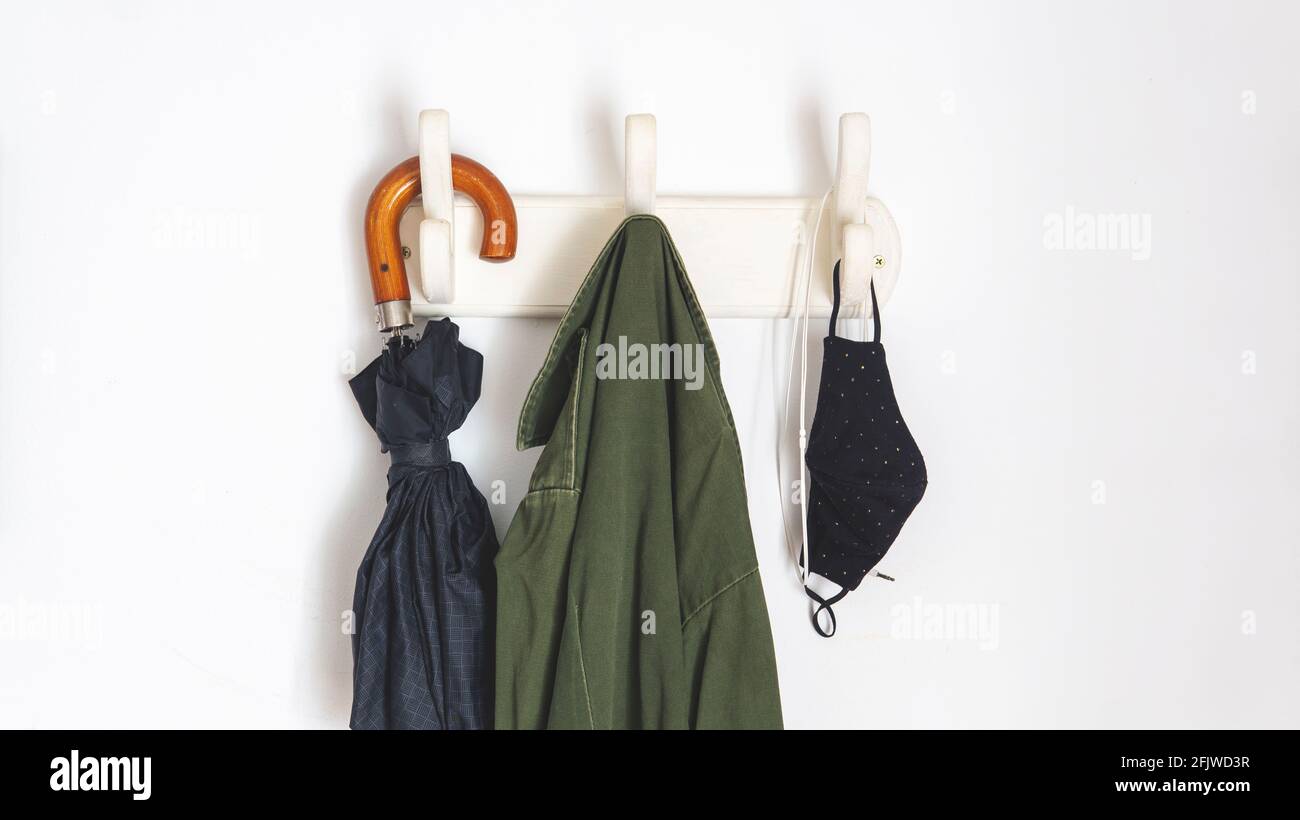 les choses dont vous avez besoin si vous sortez dans la nouvelle normale en raison de covid-19. Pendre d'un porte-manteau un parapluie, un manteau, des masques faciaux et un casque Banque D'Images