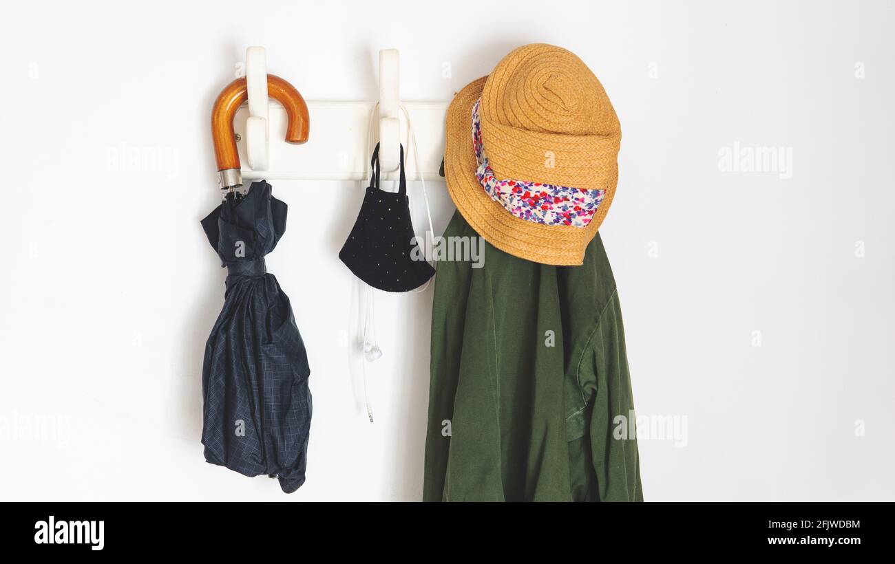 les choses dont vous avez besoin si vous sortez dans la nouvelle normale en raison de covid-19. Pendre d'un porte-manteau un parapluie, un manteau, des masques faciaux et un casque Banque D'Images