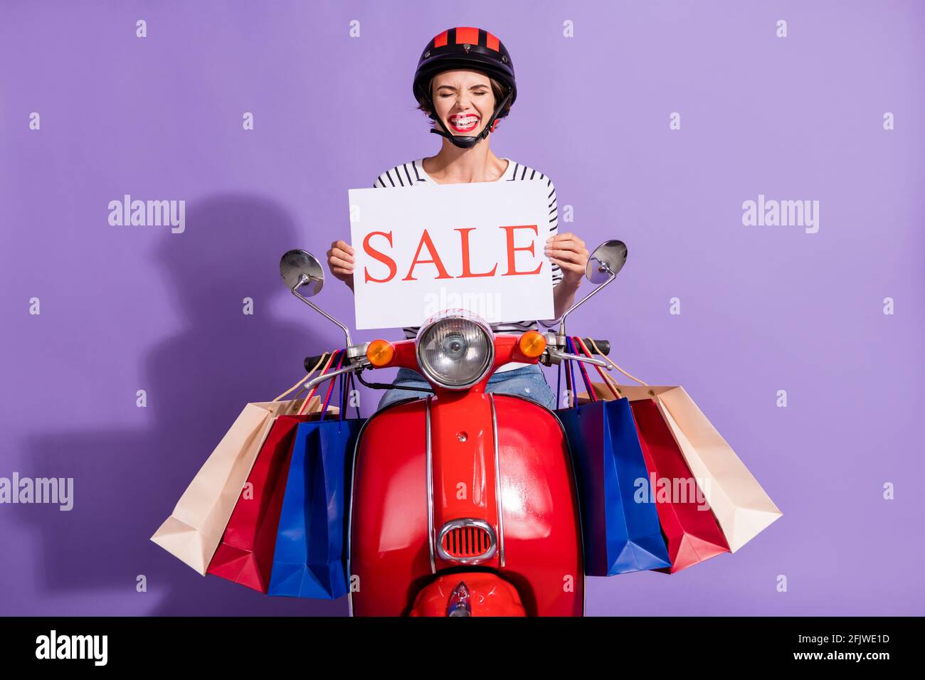 Photo de drôle moto dame vêtue de vêtements rayés casque rouge salon moto  tenue vente affiche isolé couleur violet arrière-plan Photo Stock - Alamy