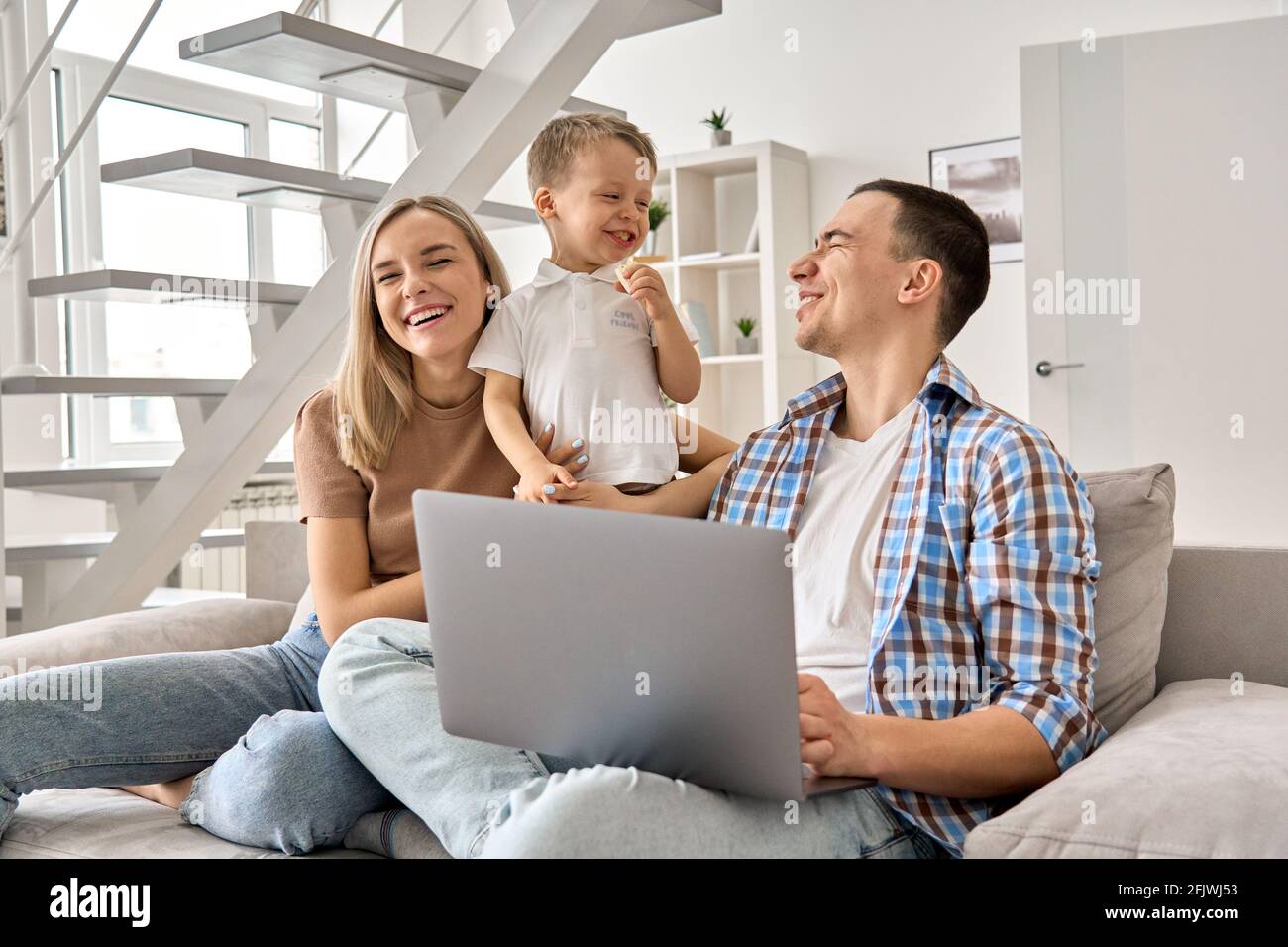 Bonne famille maman, papa et enfant mignon fils s'amuser en utilisant l'ordinateur portable à la maison. Banque D'Images