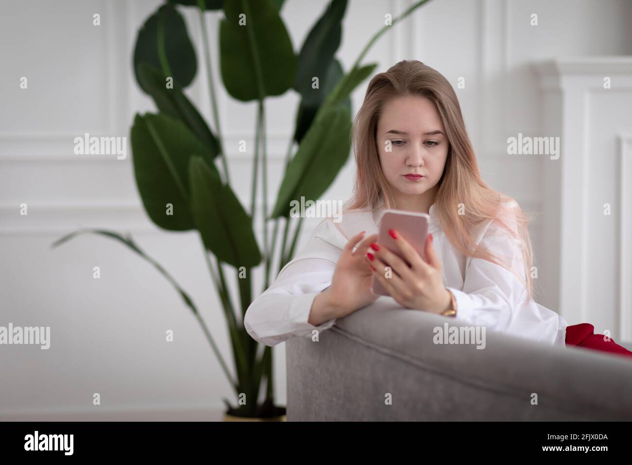 Une jeune femme tape du texte dans le téléphone et regarde l'écran du smartphone. Concept de communication en ligne sur Internet et les réseaux sociaux. Banque D'Images
