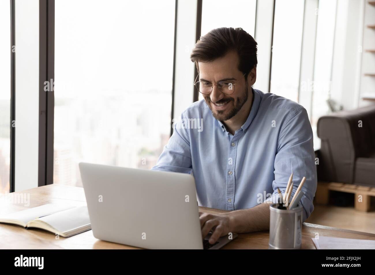 Un homme souriant travaille sur un ordinateur portable qui navigue sur Internet Banque D'Images