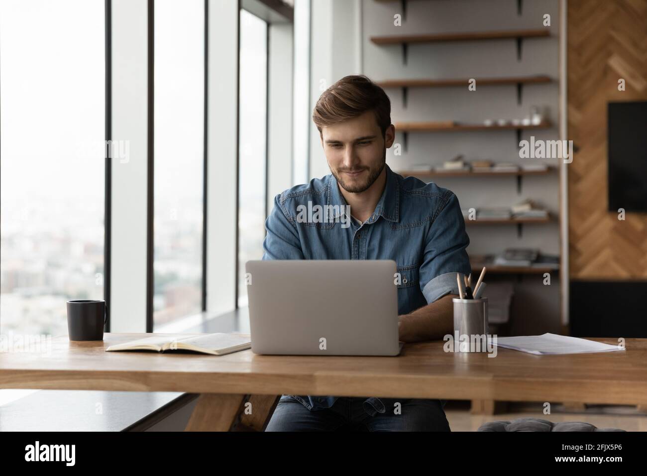 Un jeune homme travaille sur un ordinateur portable au bureau à domicile Banque D'Images