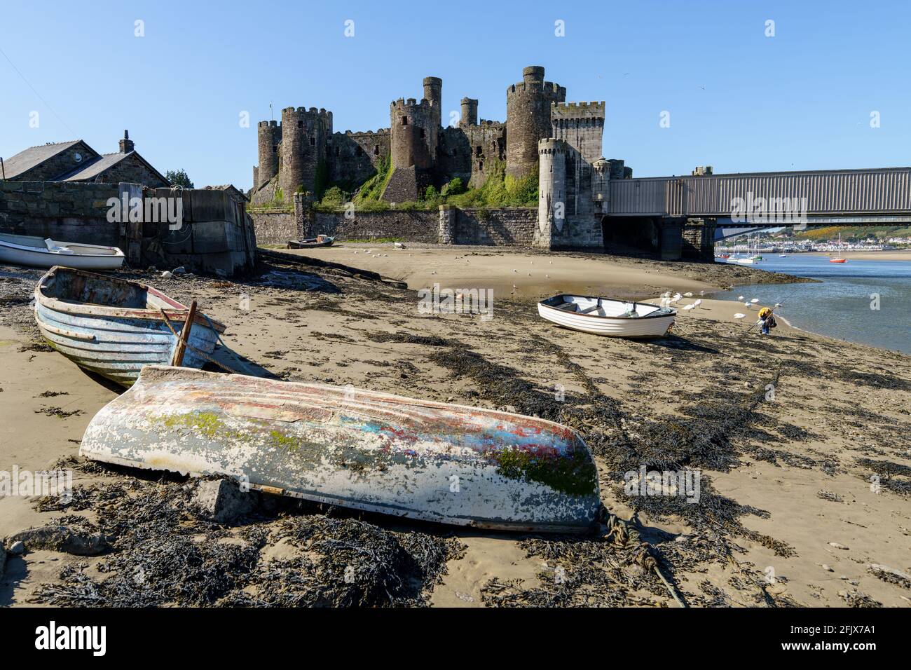 Conway château nord du pays de Galles Royaume-Uni plage avec vieux bateaux dedans le ciel bleu d'avant-plan ensoleillé jour d'été Banque D'Images
