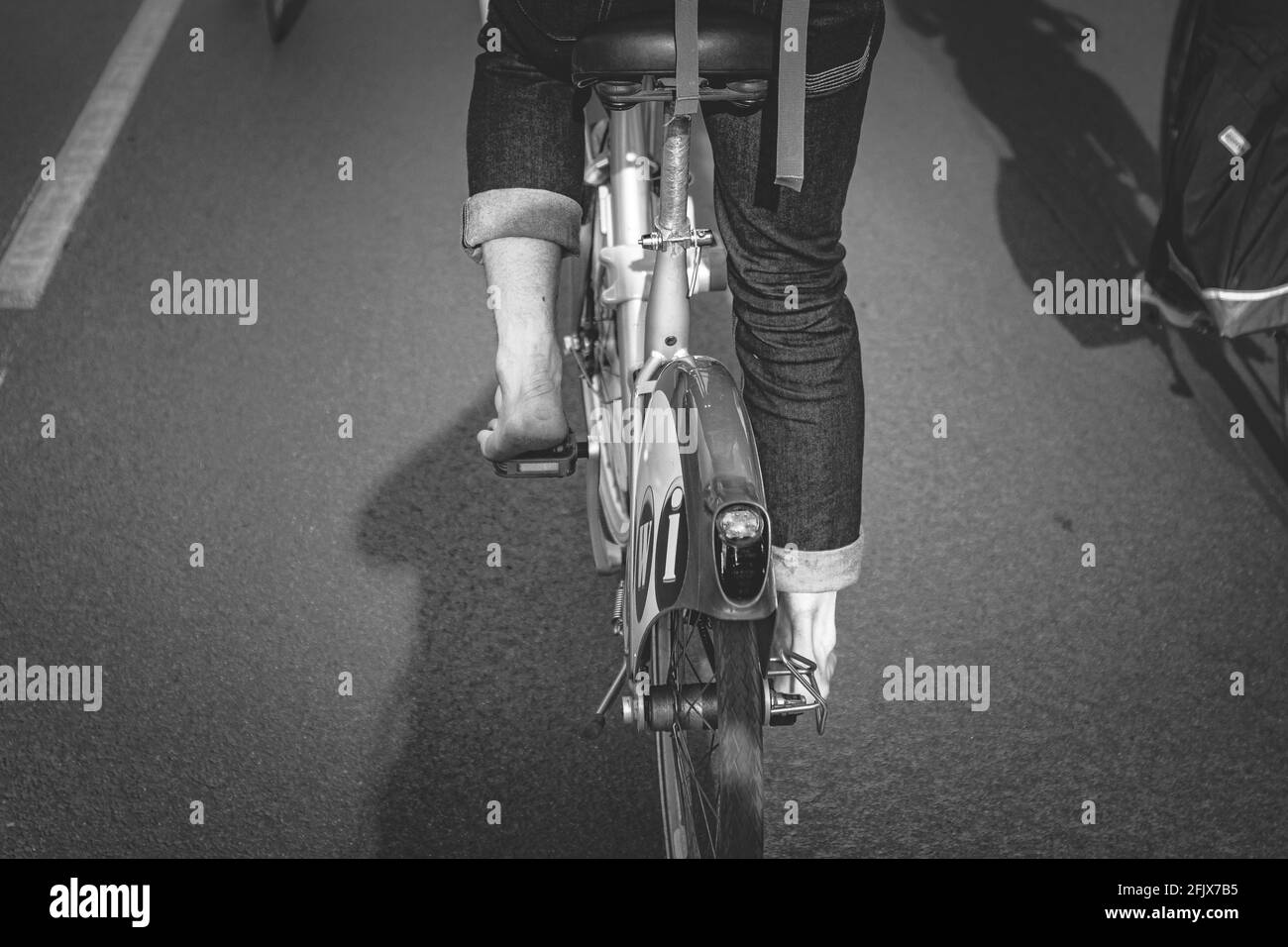 Conduite d'un vélo public pieds nus, noir et blanc, vue arrière Banque D'Images