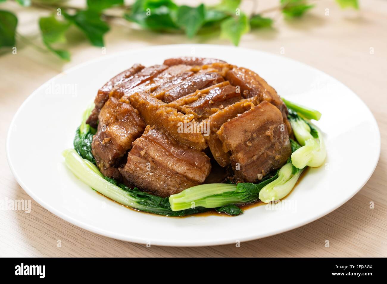 Poitrine de porc braisée avec igname servie avec des légumes verts Banque D'Images