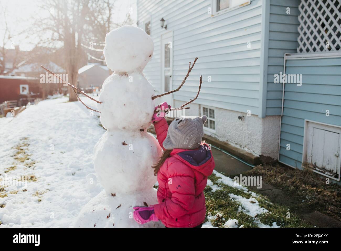 Père et fille construisent bonhomme de neige à l'extérieur de la maison Banque D'Images