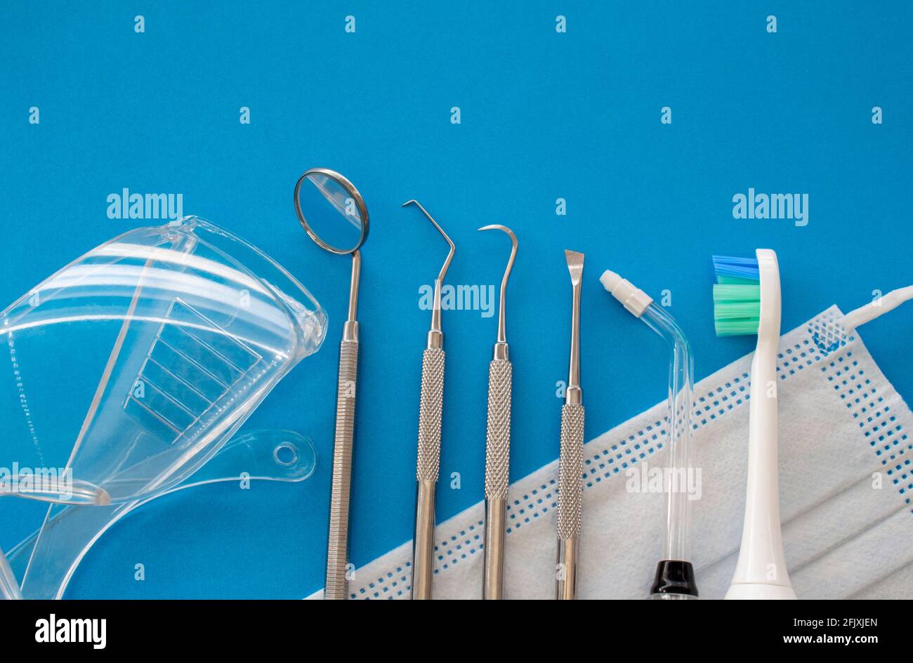 Outils de dentiste sur surface bleue gros plan. Outils de nettoyage professionnels pour l'hygiène dentaire. Set de décapant pour calculs et plaques, scaler dentaire et miroir de bouche Banque D'Images