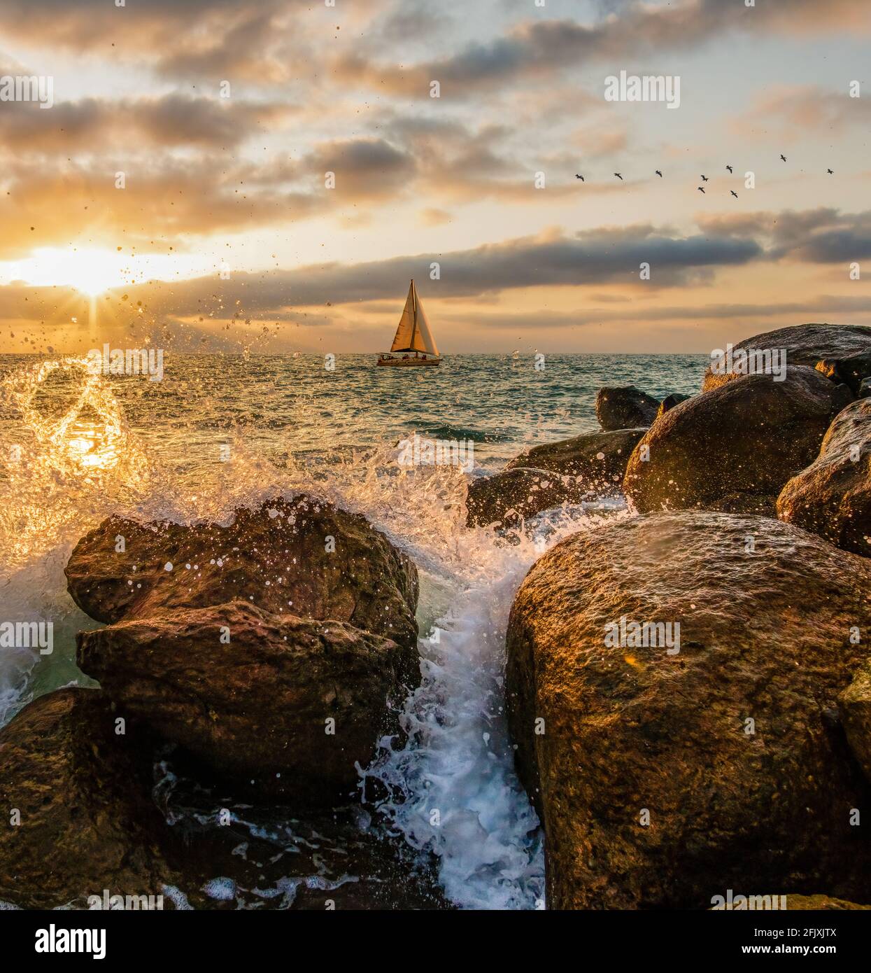 Un Voilier est la voile le long de l'océan coucher de soleil comme UN Des vagues éclabousser sur terre dans UN format d'image vertical Banque D'Images