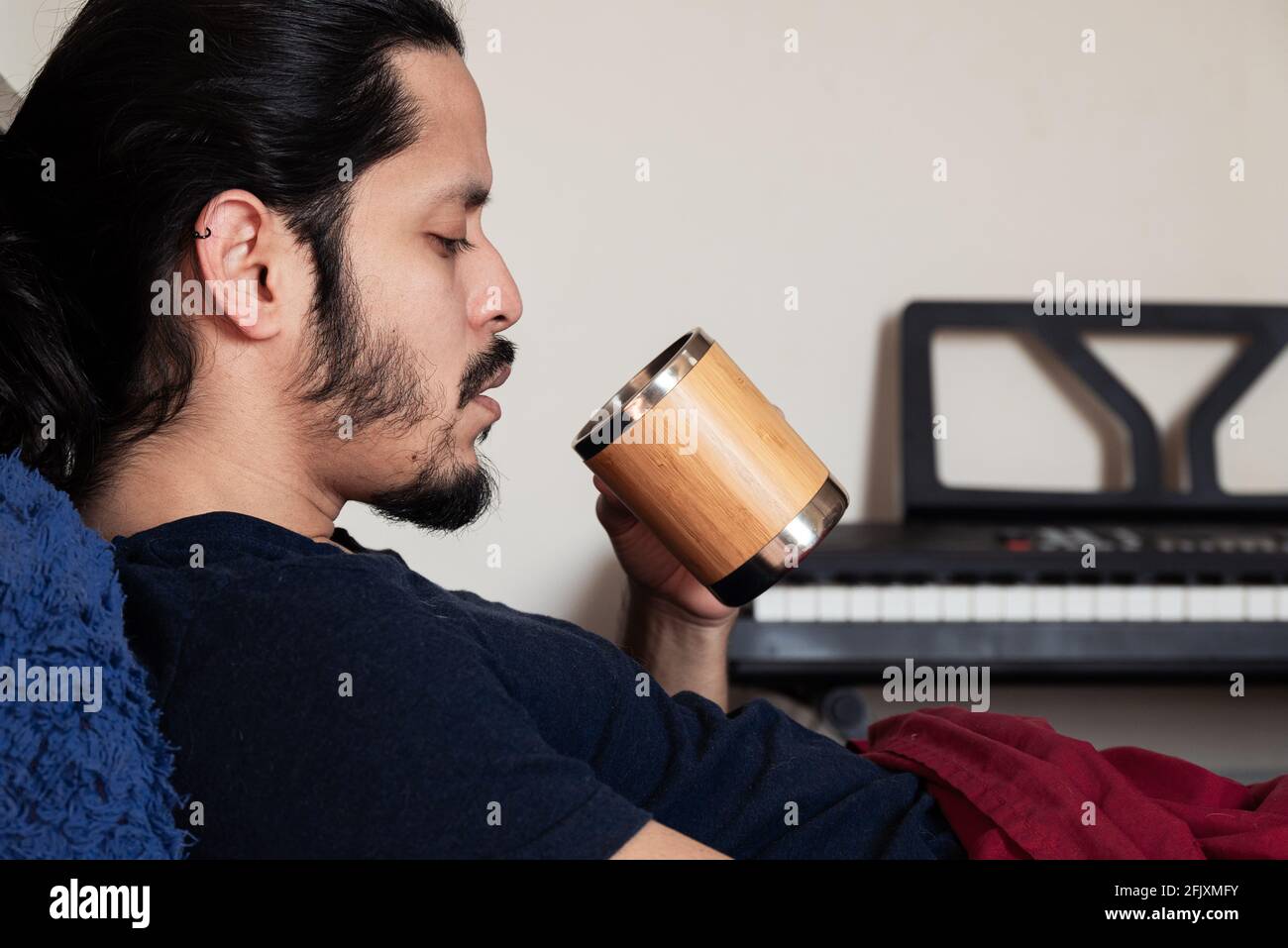 Jeune latino malade au lit à la maison en buvant un tasse de thé Banque D'Images