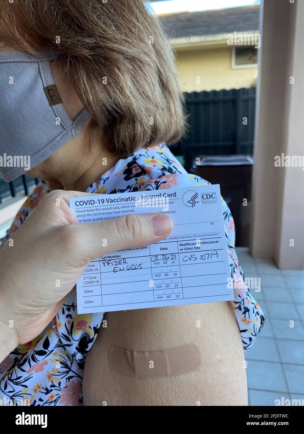 Gros plan de la fiche de vaccination COVID-19 par les CDC. Femme âgée masquée après avoir reçu le vaccin Covid-19 à sa pharmacie locale, montrant le CVS Banque D'Images Gros plan de la fiche de vaccination COVID-19 par les CDC. Femme âgée masquée après avoir reçu le vaccin Covid-19 à sa pharmacie locale, montrant le CVS Banque D'Images