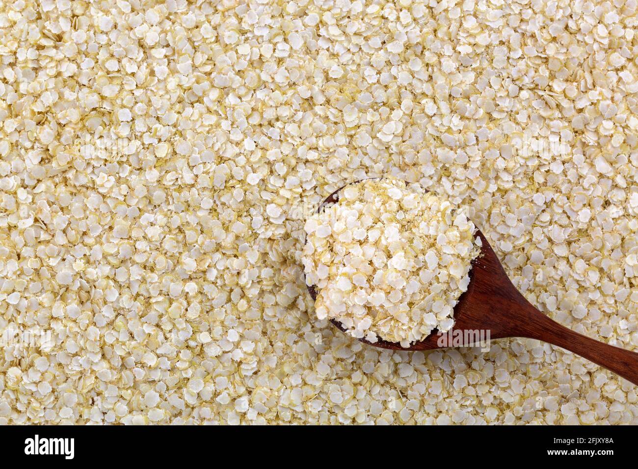 Cuillère de flocons de quinoa blanc roulé sans gluten. Grains organiques aplatis riches en protéines, fibres alimentaires, vitamines B, minéraux alimentaires (Chenopodi Banque D'Images